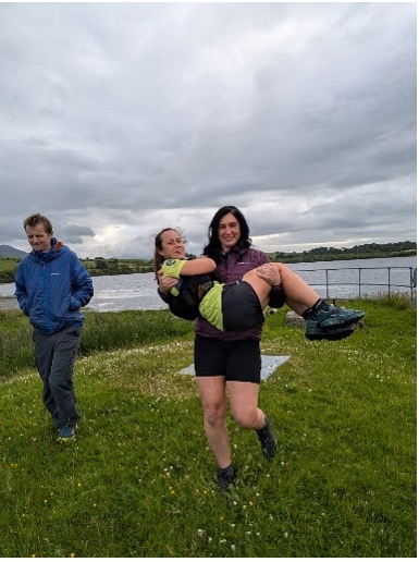 A woman carrying Megan away from a lake with a smiling man next to them.