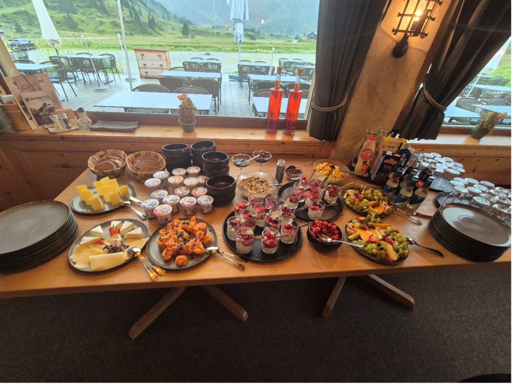 A table of buffet food against a window with a backdrop of Austrian mountains at the adidas TERREX Infinite Trails in Gastein