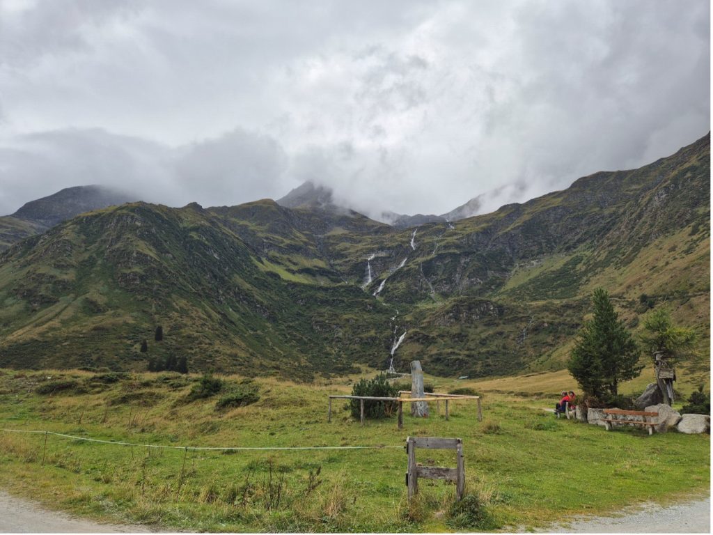 A scenic mountain image with green fields in the foreground and a stream rushing down a green mountainside at adidas TERREX Infinite Trails in Gastein