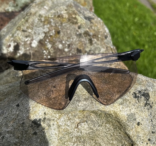 Black sports sunglasses resting on a sunlit rock outdoors
