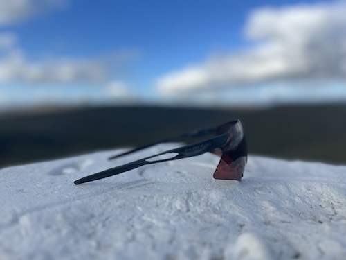Rudy Project Astral Sphere sunglasses with a dark wraparound frame and tinted lens against a snowy landscape.
