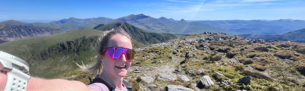 Runner takes a selfie on a rocky Welsh ridge, with mountains stretching into the distance