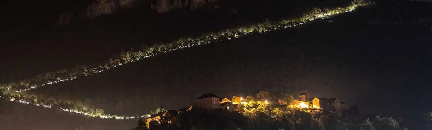 A line of runners’ headlamps winds across a dark hillside during the Diagonale des Fous.